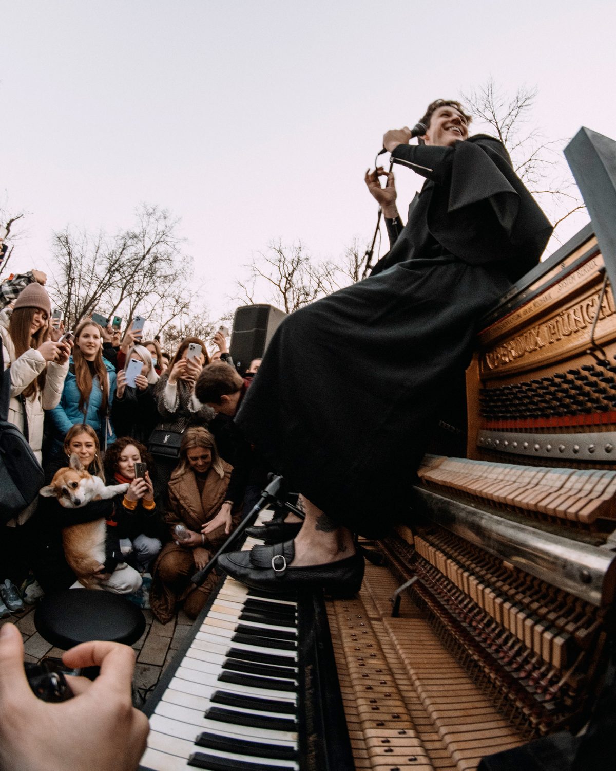 Stephen Ridley playing an open street piano surrounded by a crowd